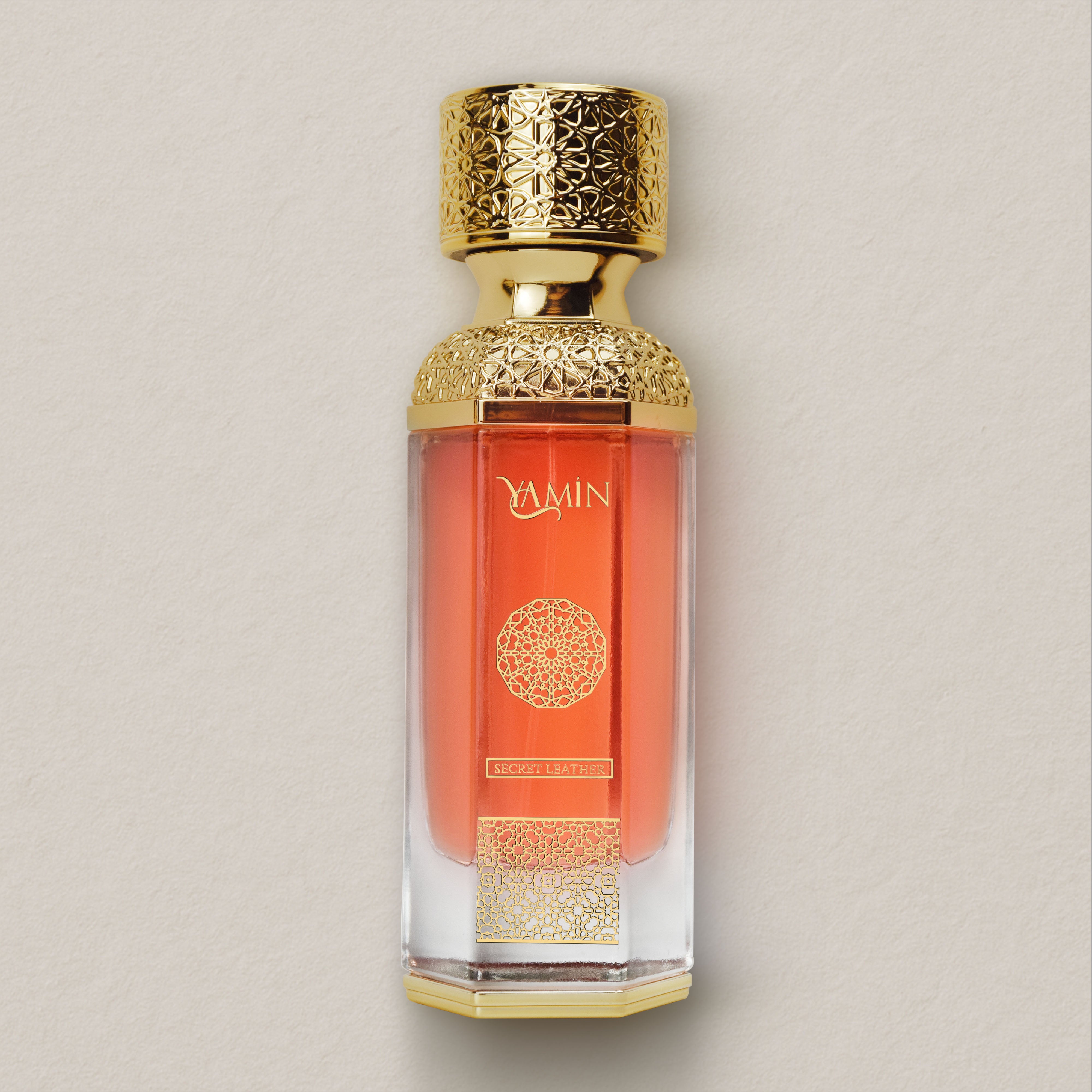 Secret Leather perfume bottle with gold cap and intricate design on a beige background